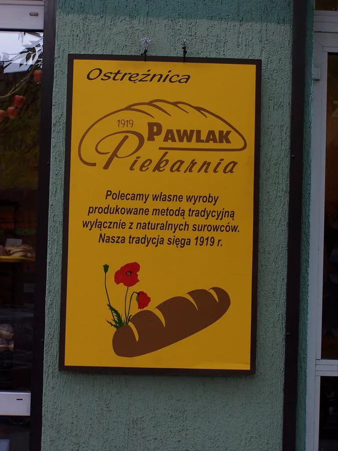Szyld piekarni z grafiką pieczywa na musztardowym tle